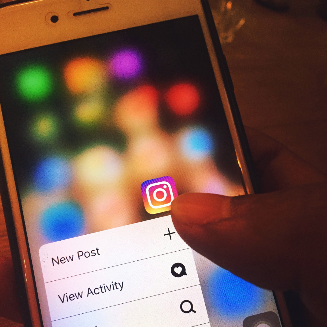 Finger hovering over Instagram logo on phone